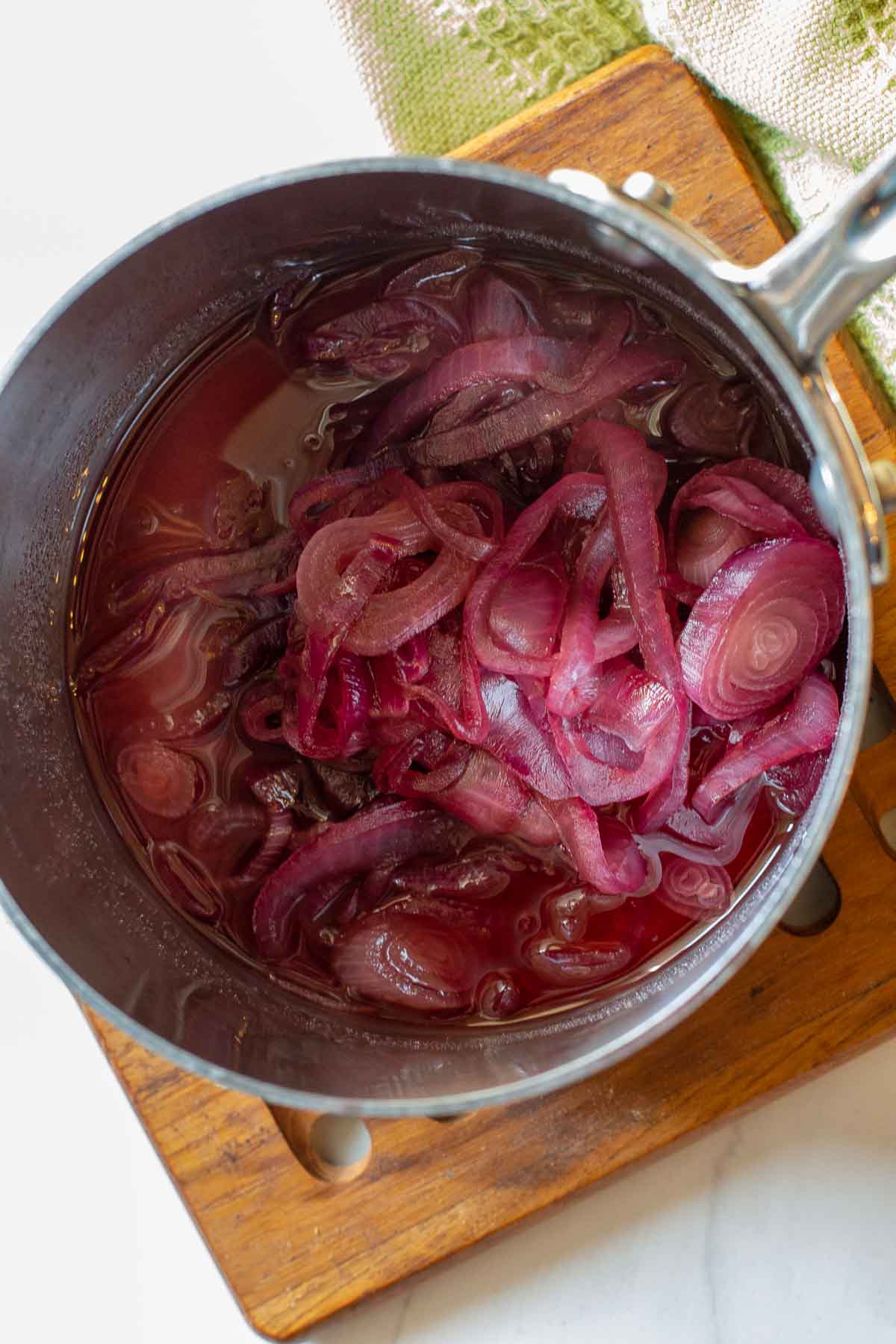 Red onions cooking in red wine vinegar to make red onion marmalade.