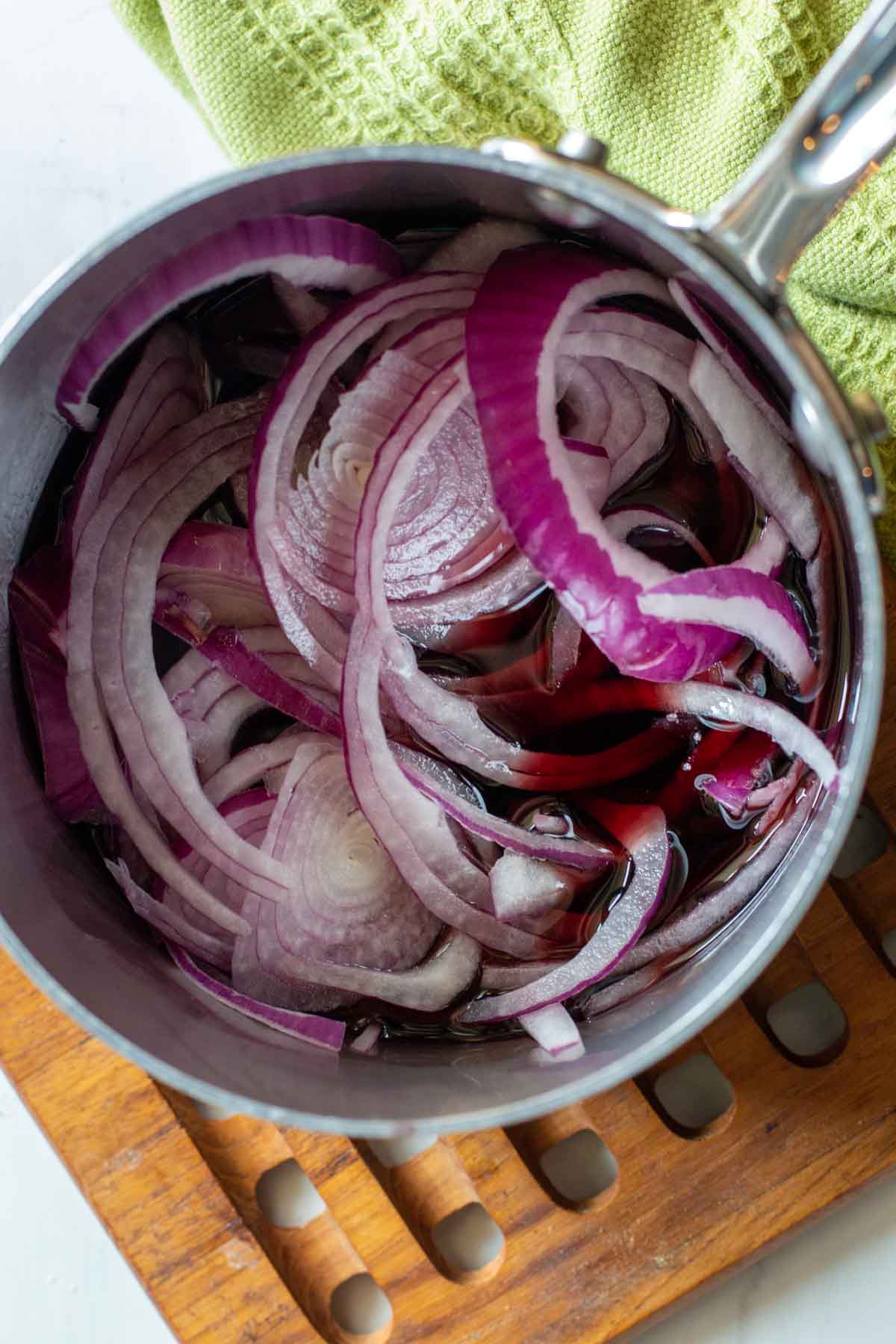 Cooking red onions in wine to make red onion marmalade.
