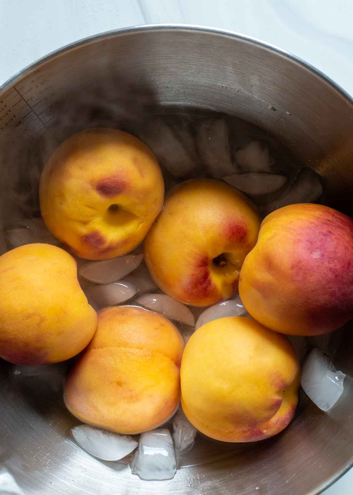 Blanched peaches in an ice bath.