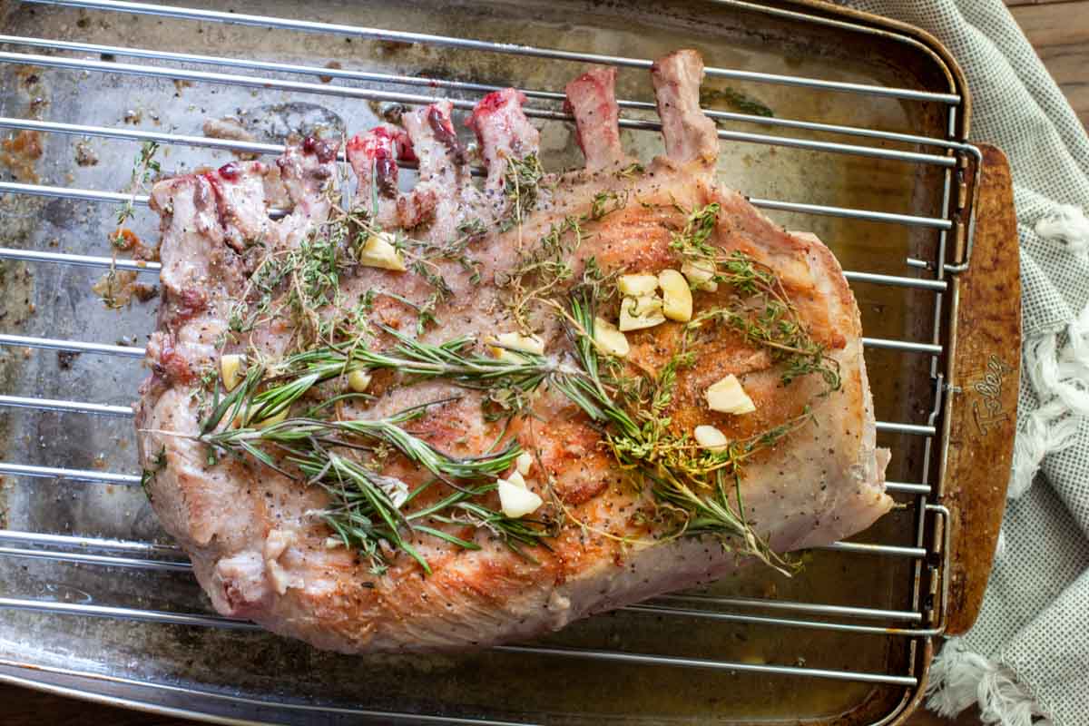 Seared rack of pork topped with fresh rosemary, thyme and smashed garlic.