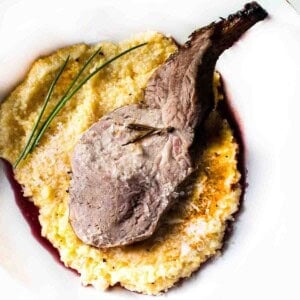 A roast rack of pork rib served over a bed of polenta.
