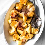 Parmesan crusted potatoes cubes in a white serving bowl.