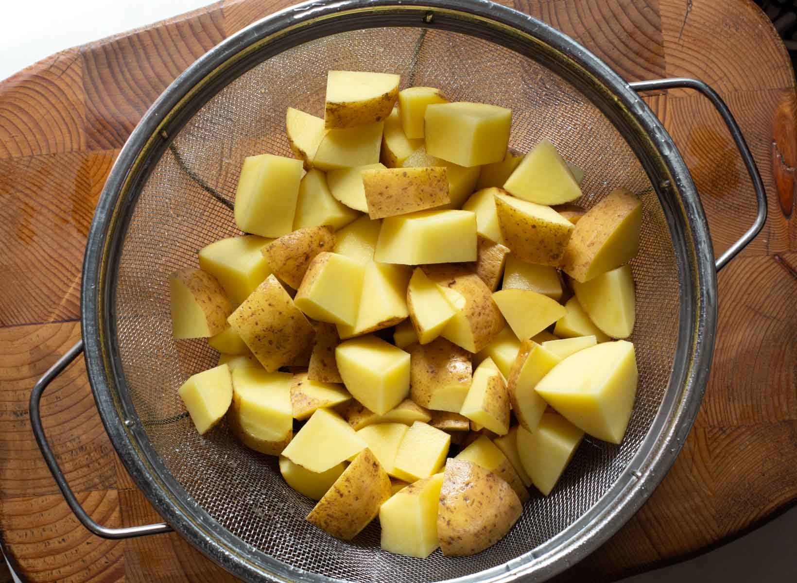 Cubed Yukon Gold potatoes in a colander to make Parmesan potaotes.