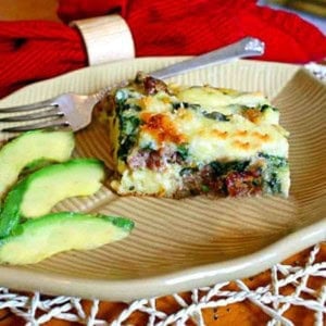 A slice of sausage biscuit bake with sliced avocados.
