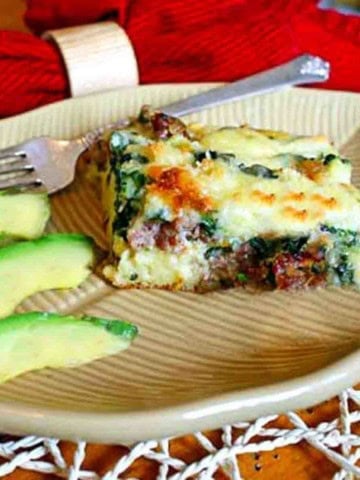 A slice of sausage biscuit bake with sliced avocados.