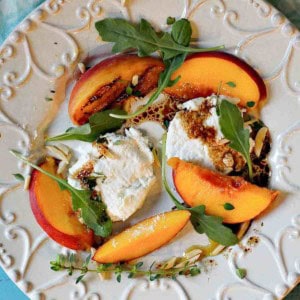 A salad with grilled peaches, arugula and goat cheese.