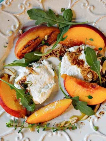 A salad with grilled peaches, arugula and goat cheese.
