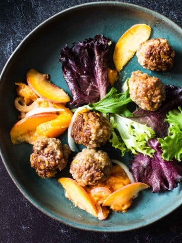Pan fried meatballs with peaches served with mixed greens.