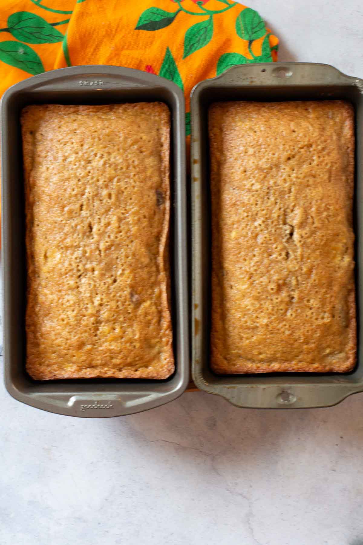 Two loafs of peach bread in loaf pans.
