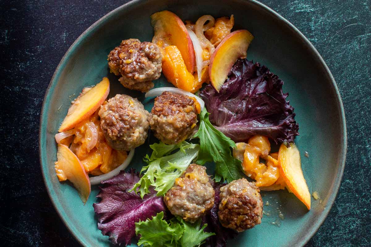 Ground pork meatballs with peaches and mixed greens.