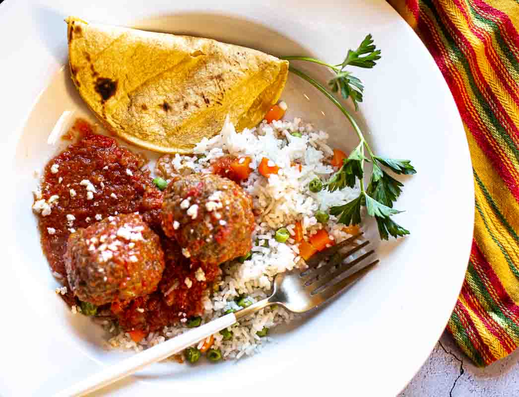 Albondigas en chipotle served with rice and a corn tortilla.