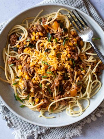 Cowboy Spaghetti with a topping of grated cheese, chopped chives.