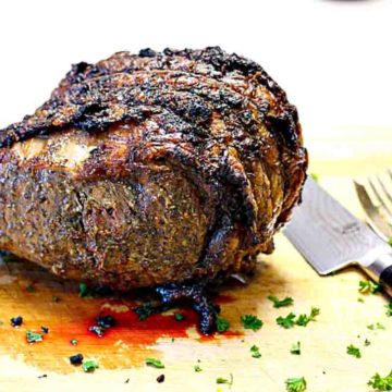Cooked bone-in prime rib roast resting on a cutting board.