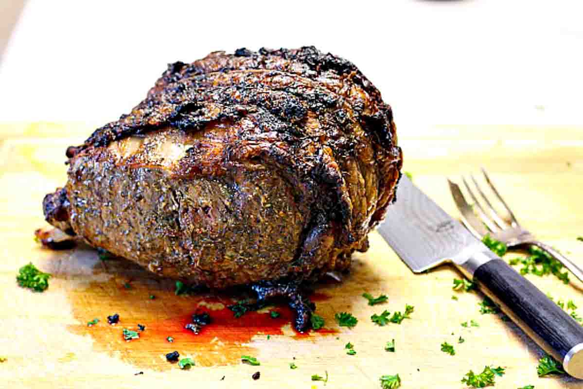 Cooked bone-in prime rib roast resting on a cutting board.