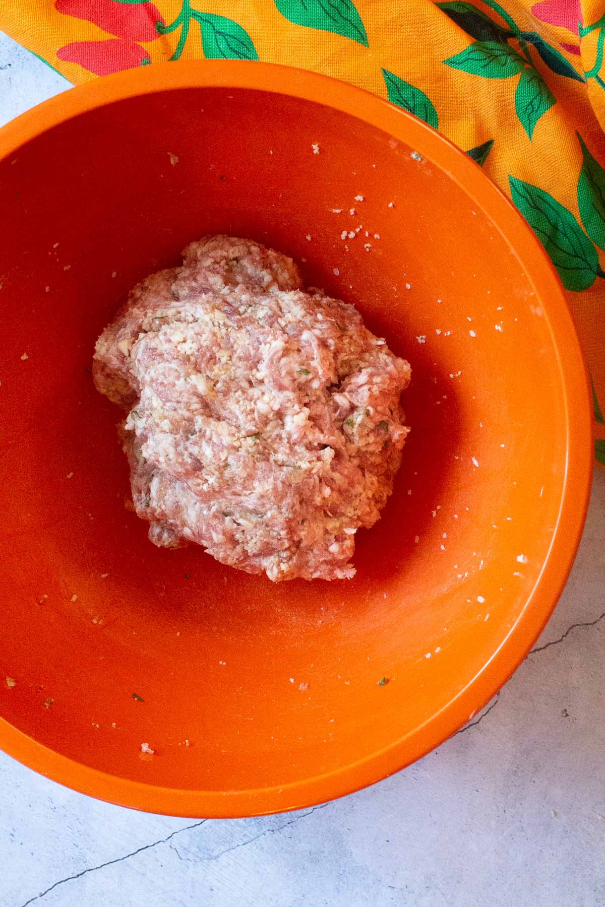 Mixing ground pork with seasonings to make pork meatballs.