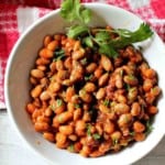 Instant pot pinto beans with chorizo served in a white bowl garnished with cilantro.