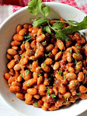 Instant pot pinto beans with chorizo served in a white bowl garnished with cilantro.