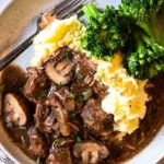 Slow cooker beef tips with gravy served with mashed potatoes and broccoli.