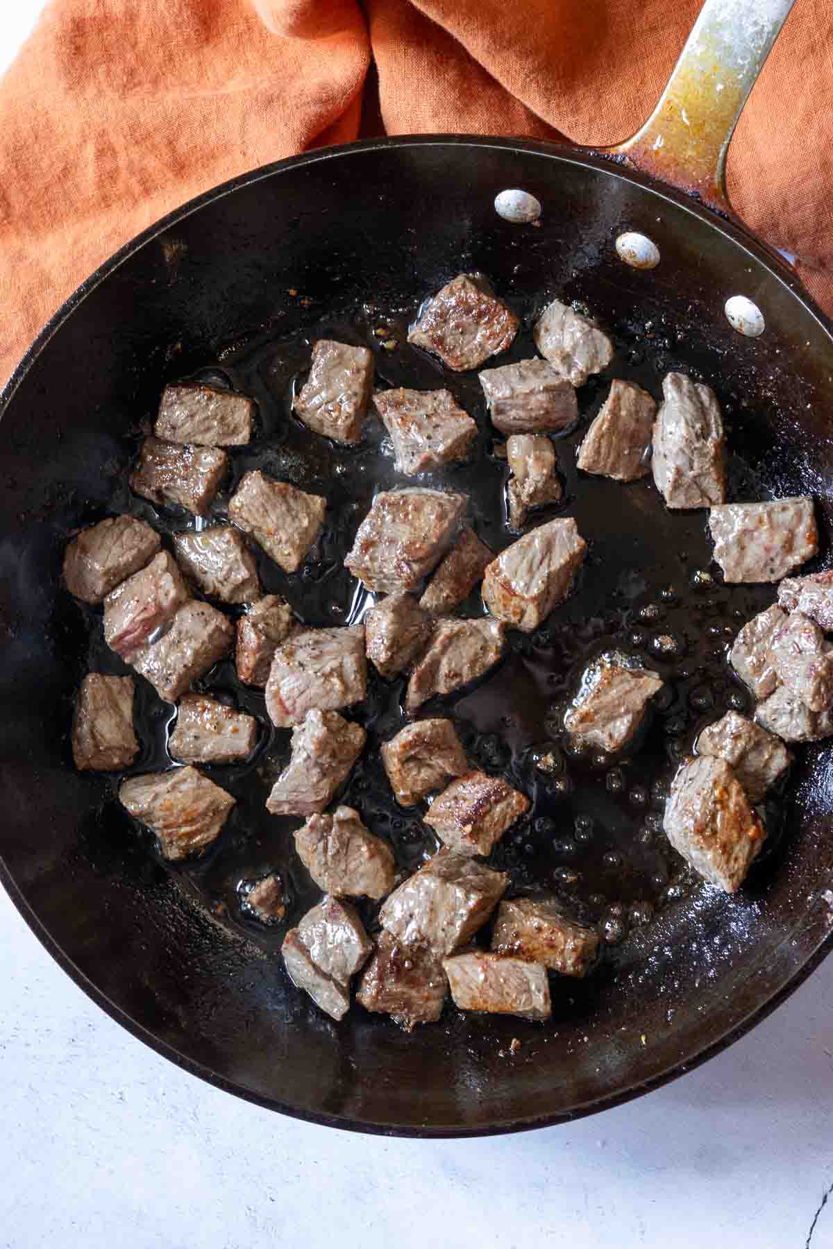 Browning round steak to make slow cooker beef tips with gravy.
