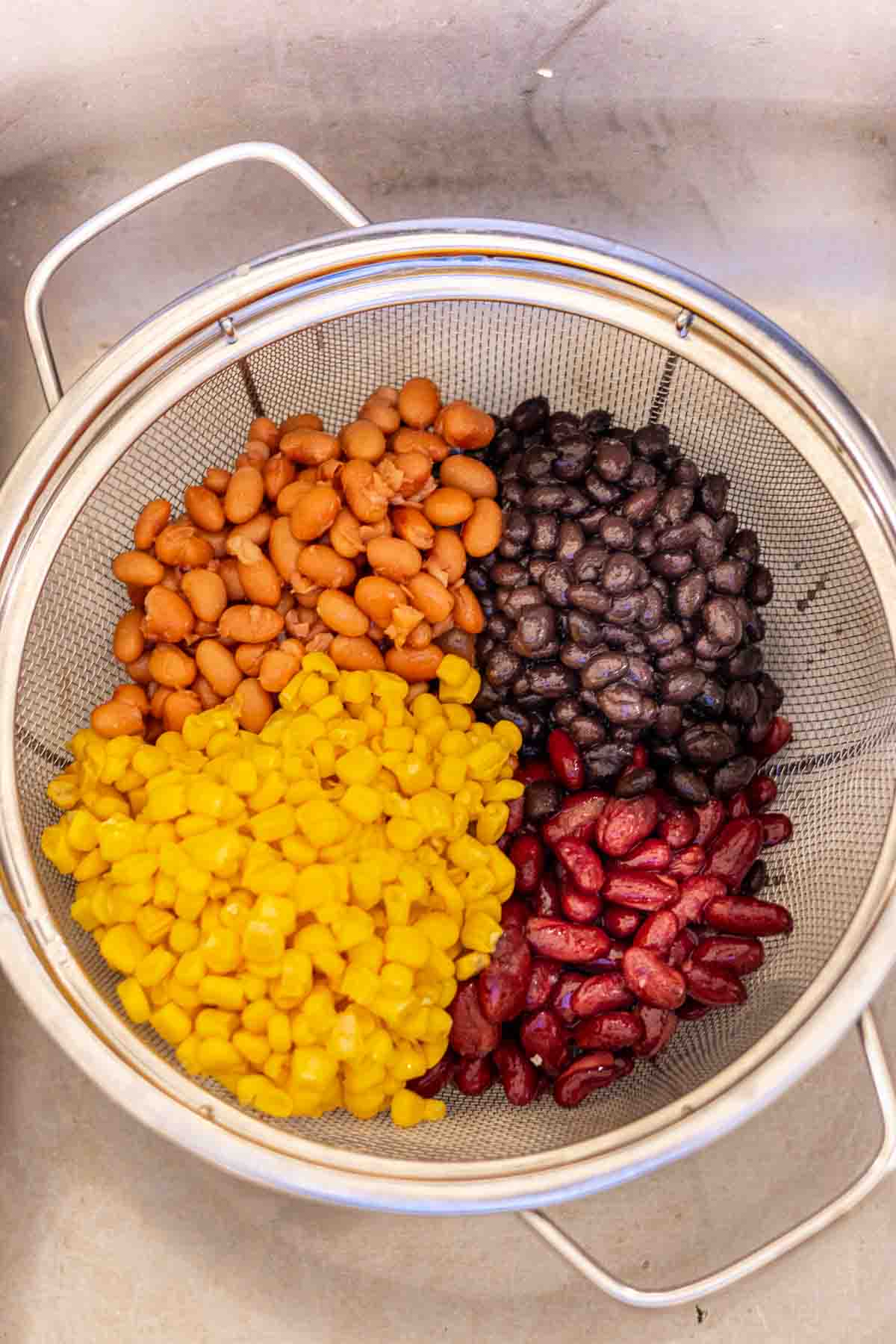 Draining beans and corn in a colander to make taco soup with ranch dressing.