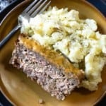 A slice of BBQ meatloaf plated with mashed potatoes.