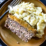 A slice of BBQ meatloaf with mustard bbq glaze and mashed potatoes.