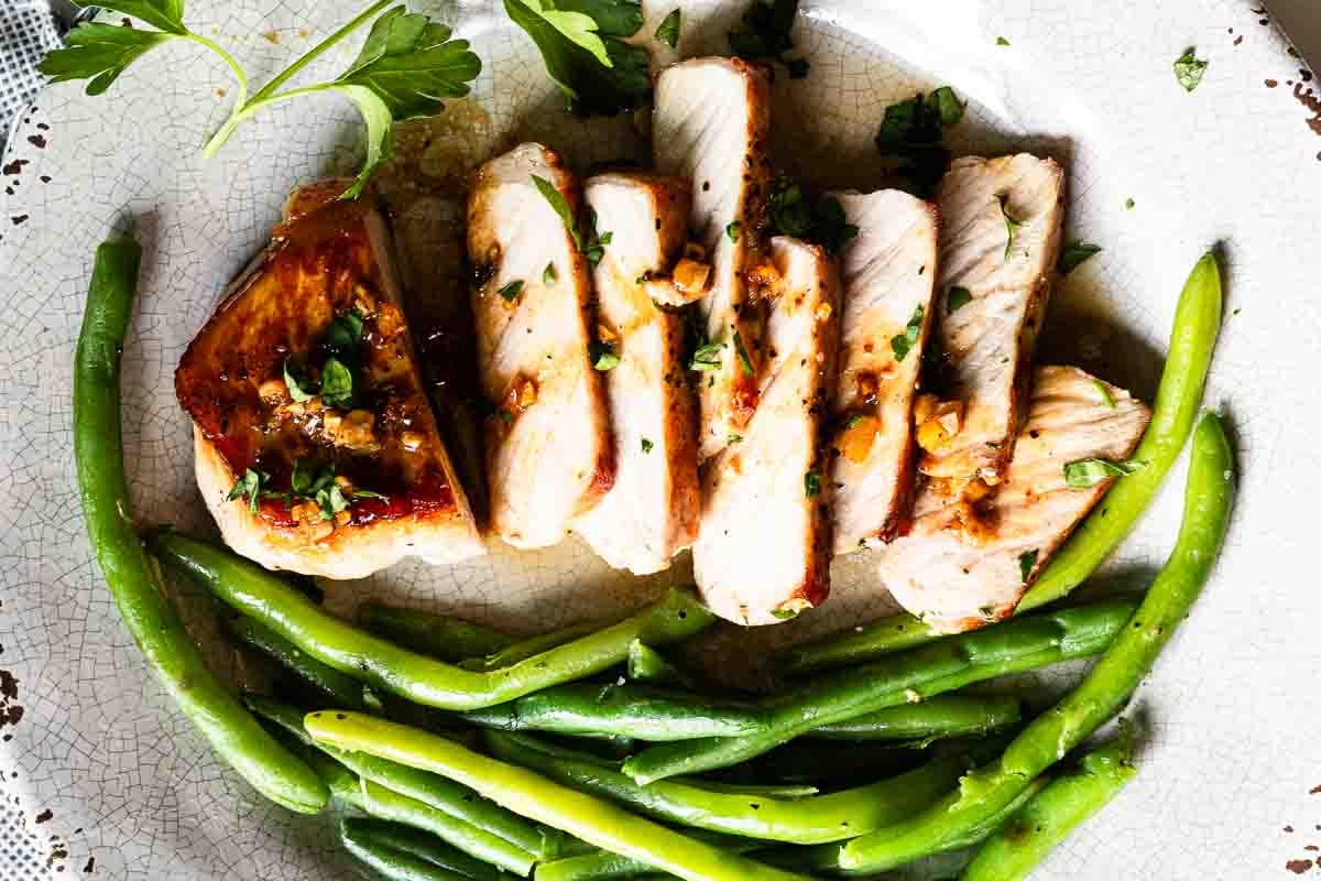 Honey garlic Pork chops sliced and served with green beans.