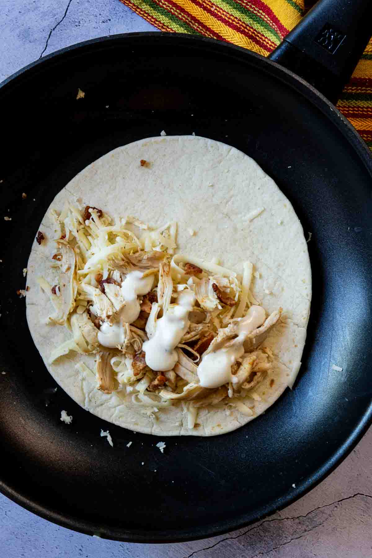 Cooking bacon chicken ranch quesadillas in a skillet.