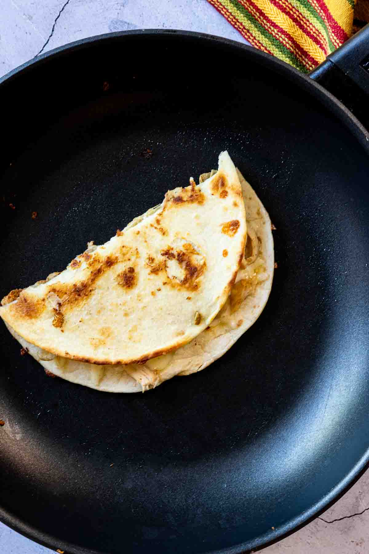 Folding chicken bacon ranch quesadilla to finish cooking.
