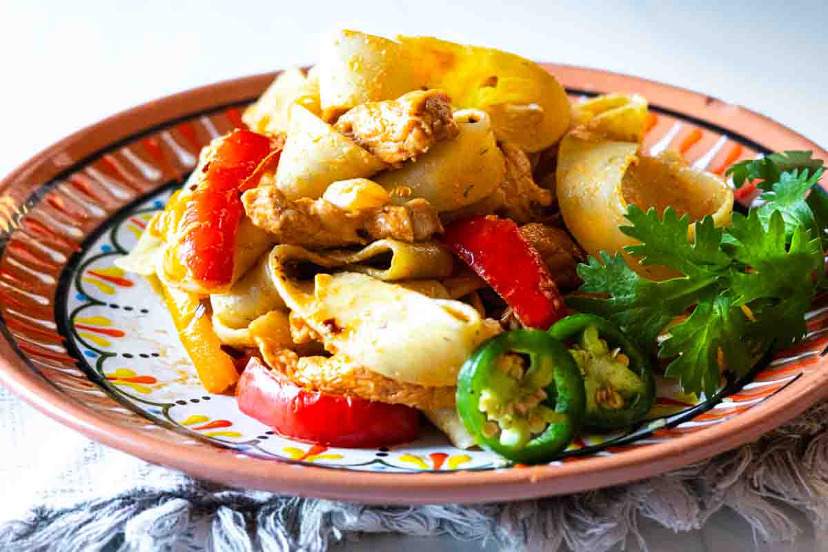 Chicken fajita pasta served on a Mexican style plate.