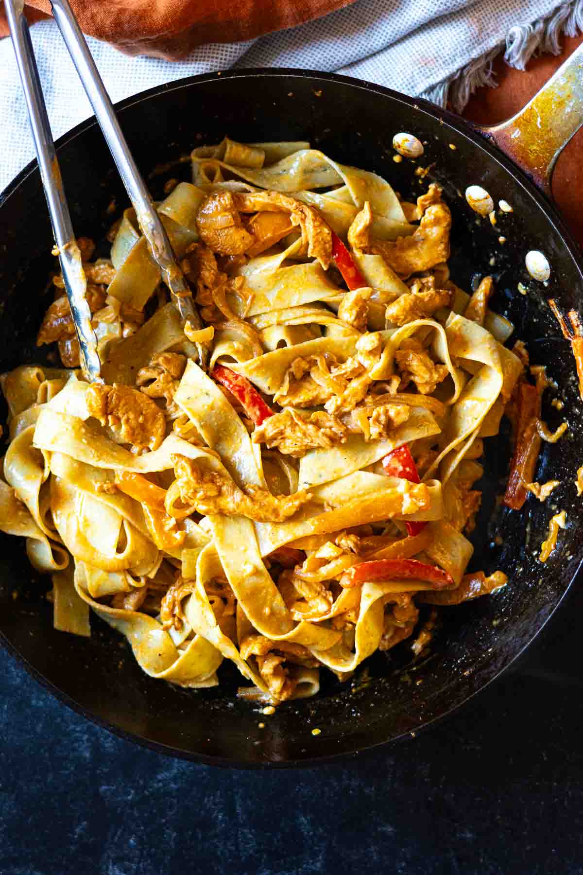 Tossing noodles with chicken and vegetables to make chicken fajita pasta.