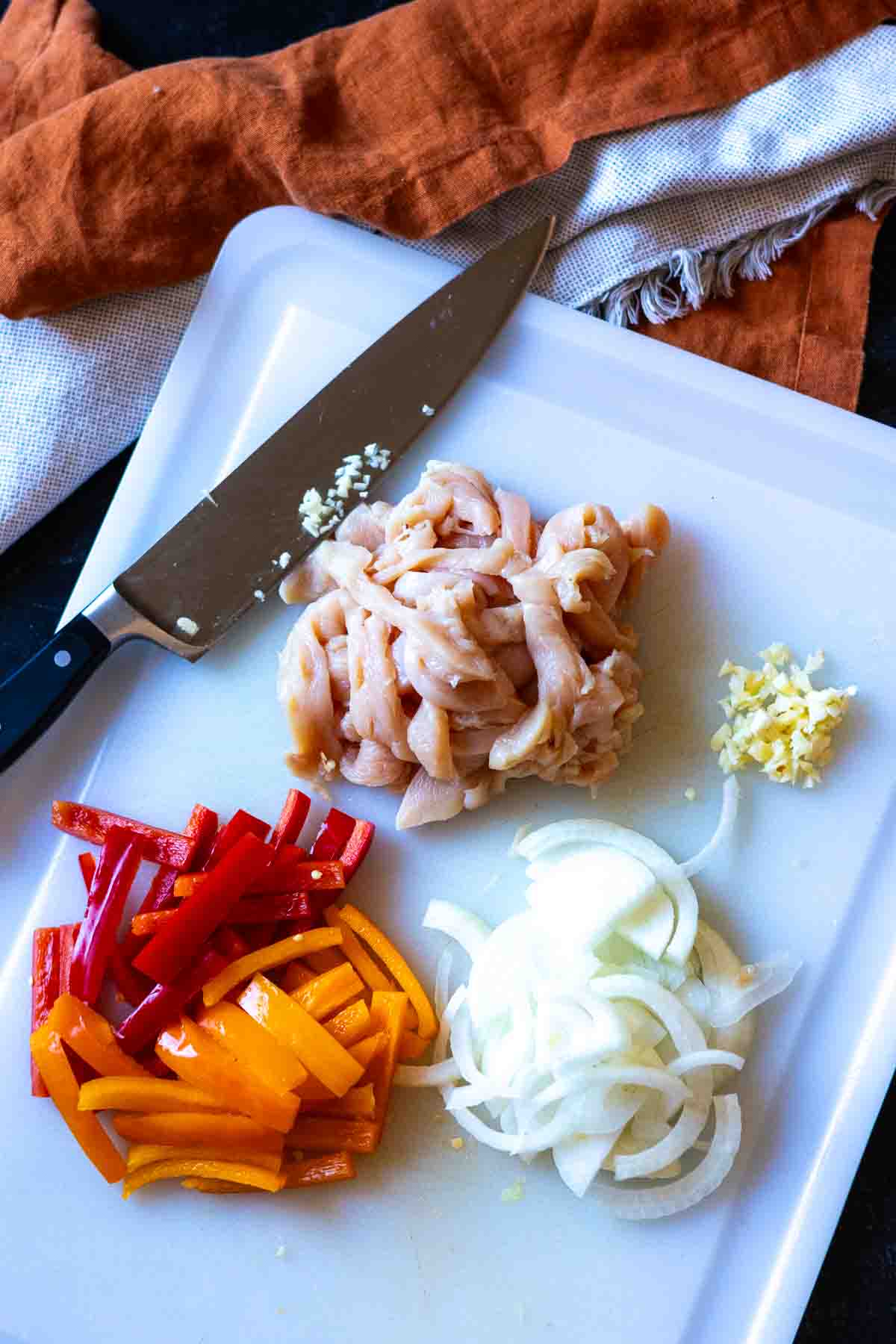 Chopping vegetables and slicing chicken to make Chicken Fajita Pasta.