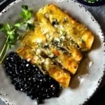 Pork enchiladas verde served with a side of black beans.