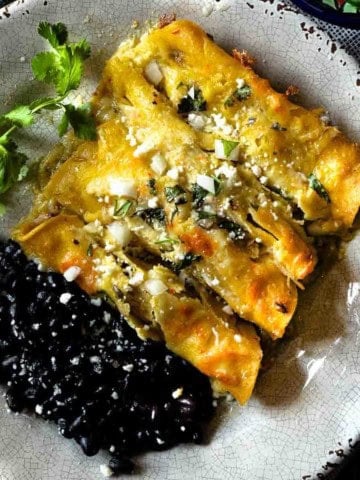 Pork enchiladas verde served with a side of black beans.