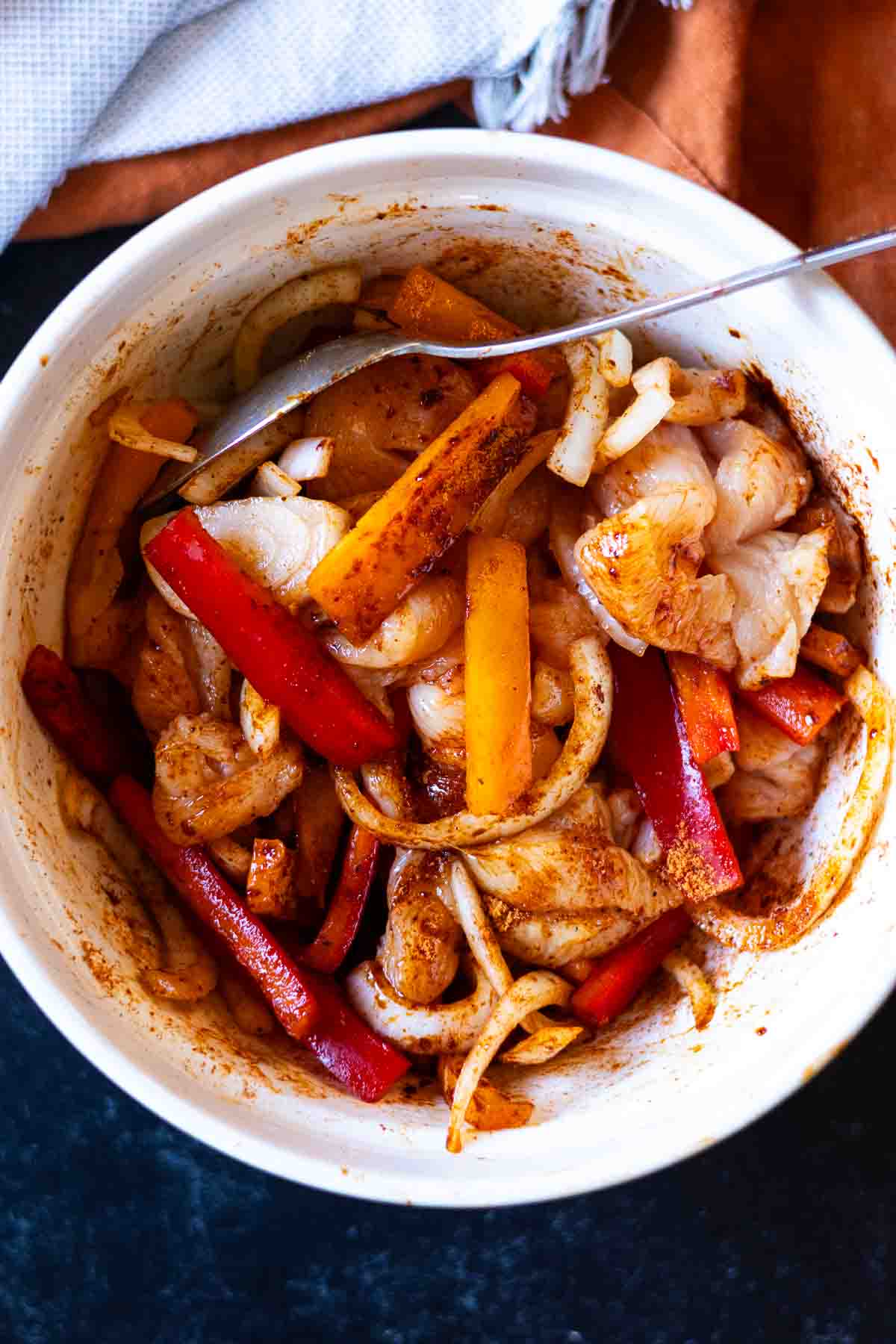 Tossing the chicken and vegetables with fajita seasoning to make Chicken Fajita Pasta.