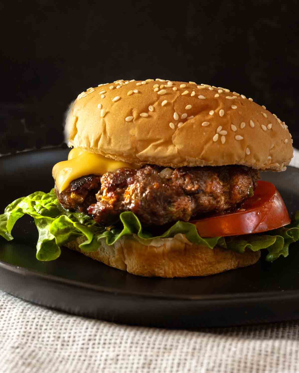 Jalapeno steak sauce burger on a sesame seed bun with american cheese, lettuce and tomato.