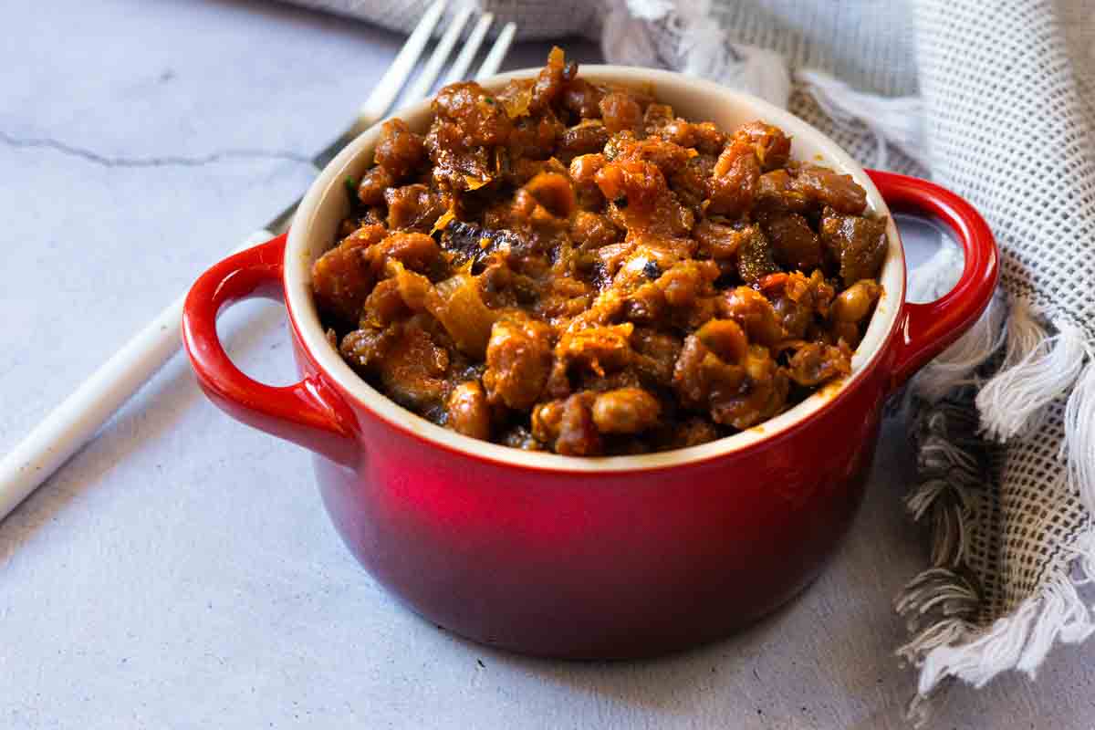 BBQ baked beans on the grill served in a red Le Creuset Ramekin.