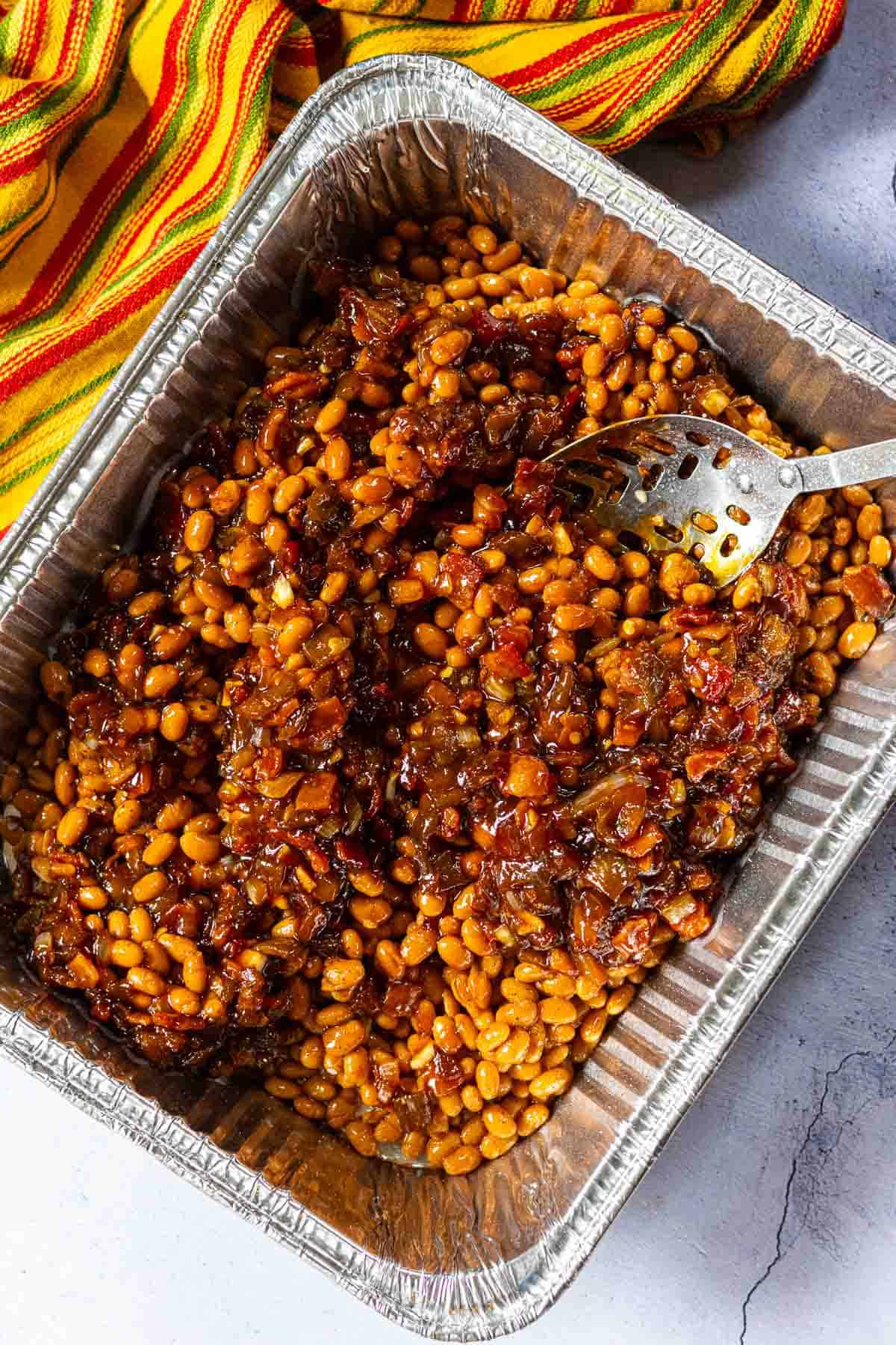 Adding sauce to canned beans to make bbq baked beans on the grill.