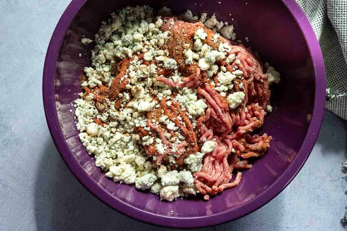 Combining ground beef and blue cheese crumbles to make black and blue burgers.