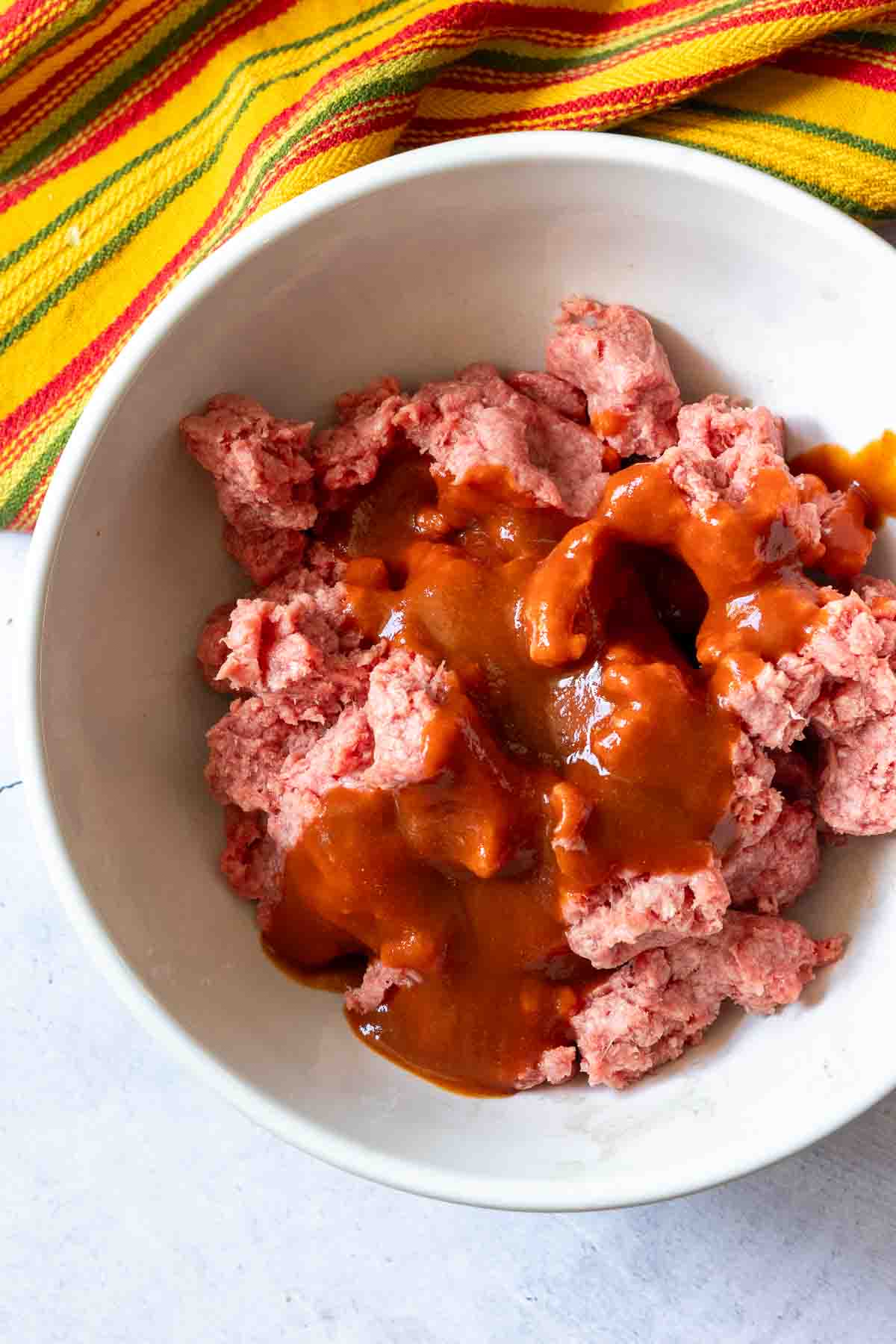 Mixing ground beef with taco sauce to make tortilla burgers.