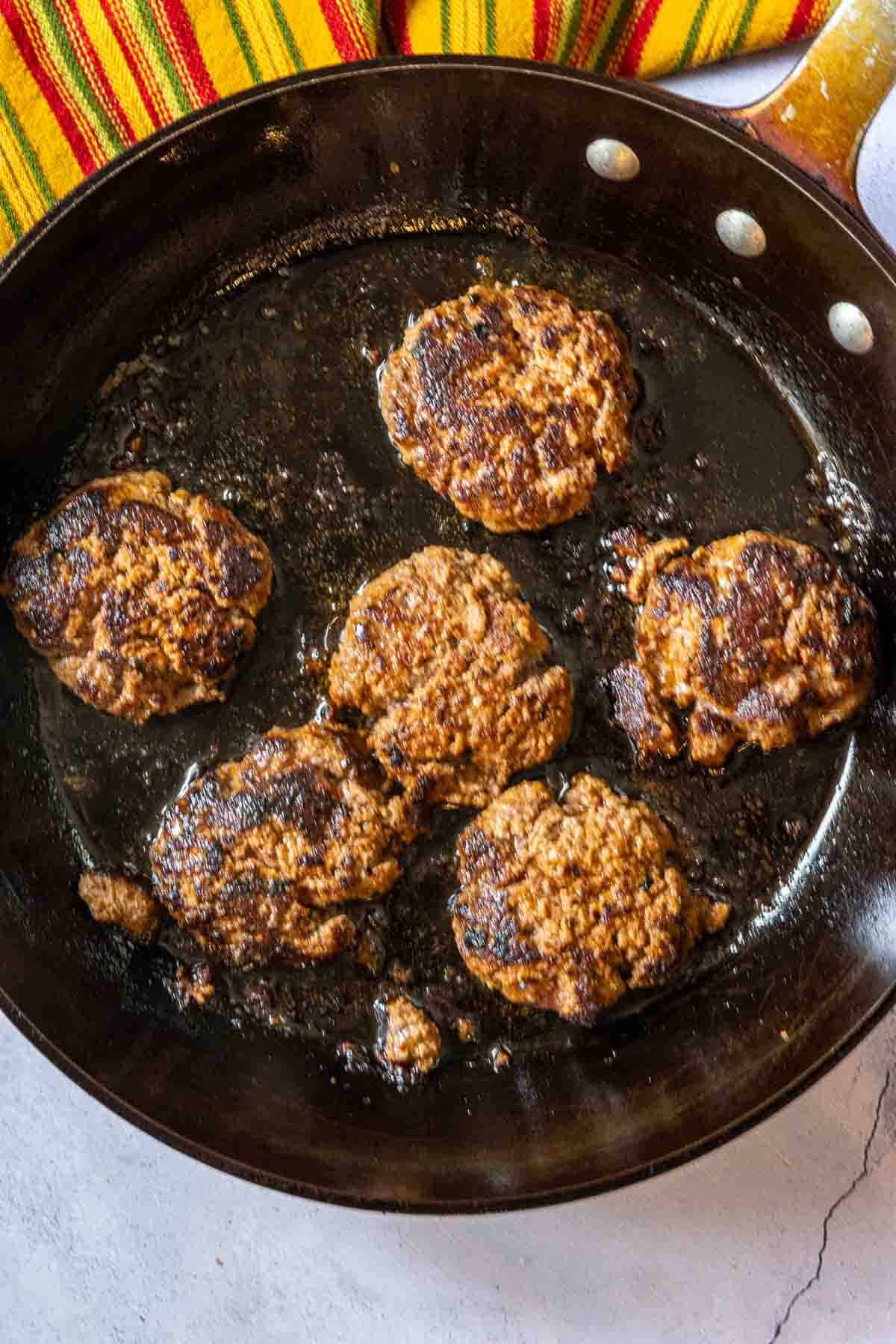 Frying tortilla burger patties in a large skillet.