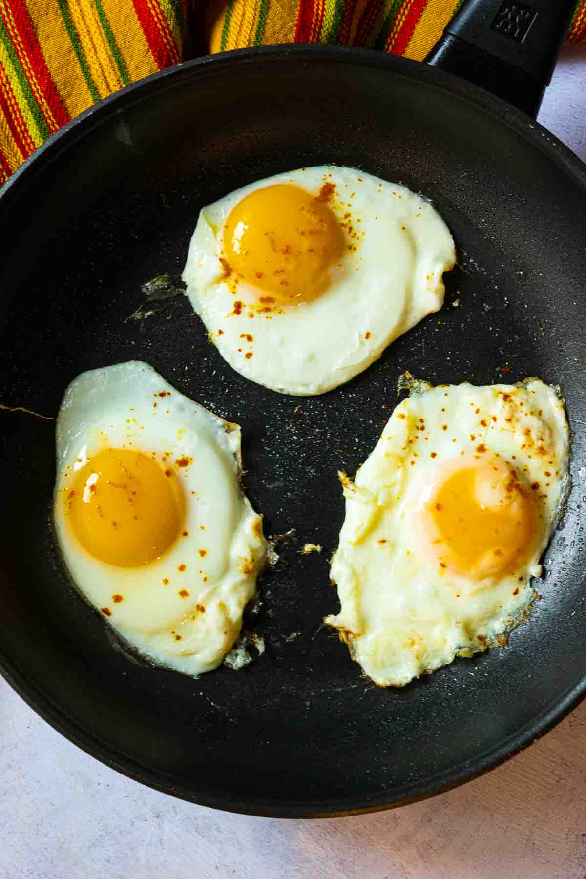 Frying eggs in a skillet to make tortilla burgers.