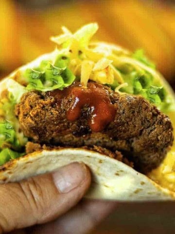 Tortilla burger in a tortilla shell with lettuce and cheese.
