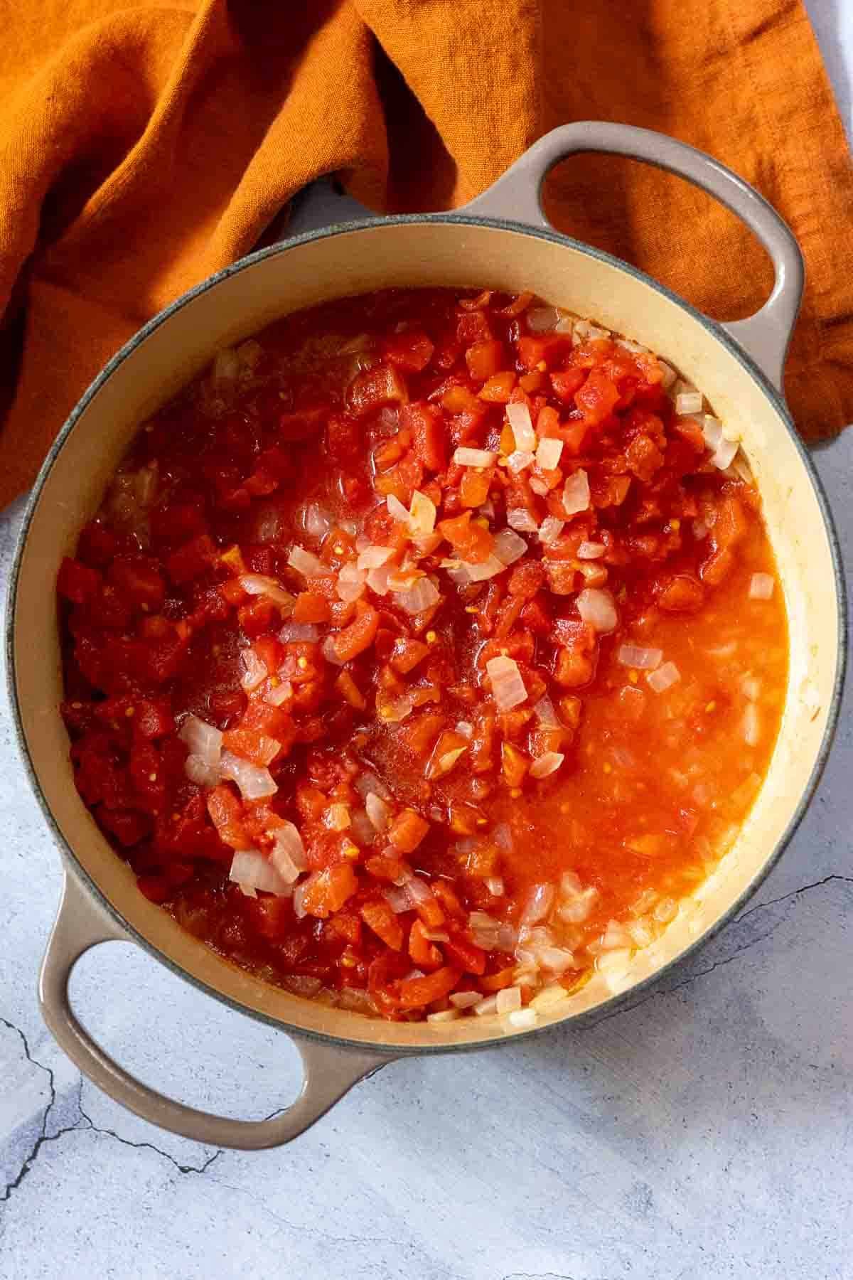 Adding canned tomatoes to make marinara sauce for shrimp and polenta.