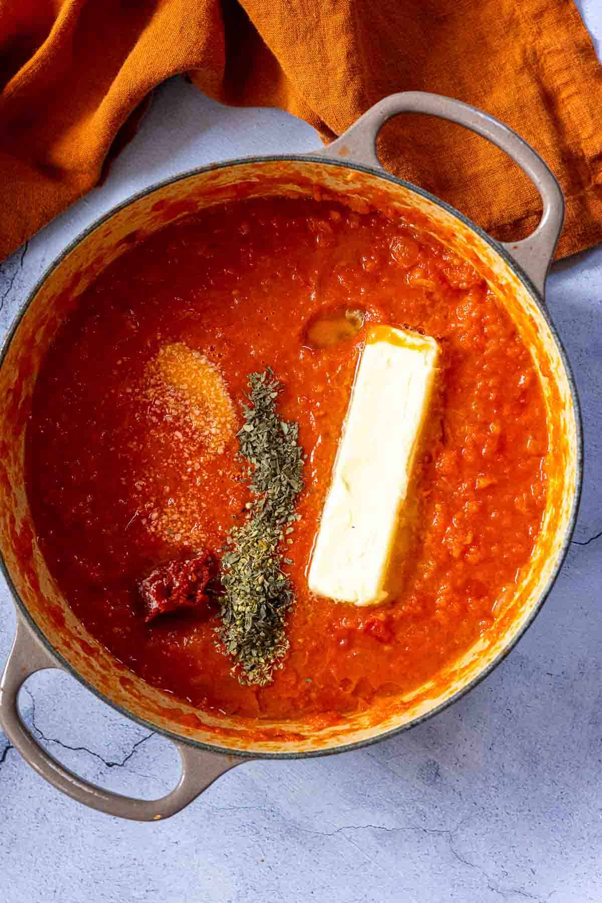 Adding seasonings and butter to sauce to simple marinara.