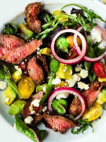 Honey glazed skirt steak salad with avocado and pickled onions.