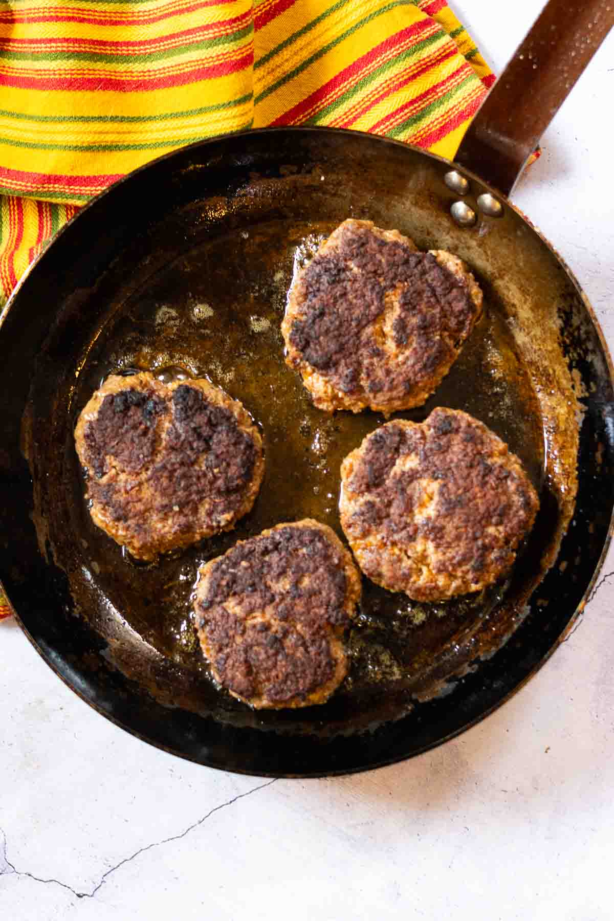 Pan frying taco burger patties in a French steel frying pan.