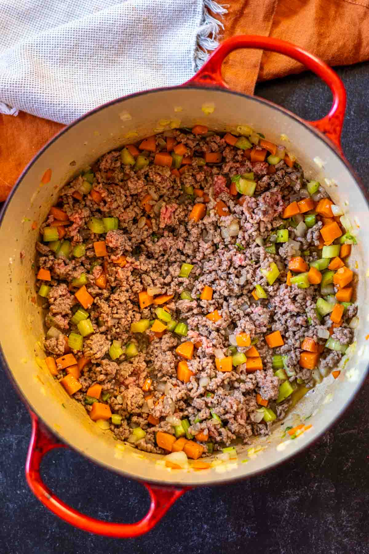Cooking hamburger with mirepoix in a Dutch oven to make hamburger potato soup.