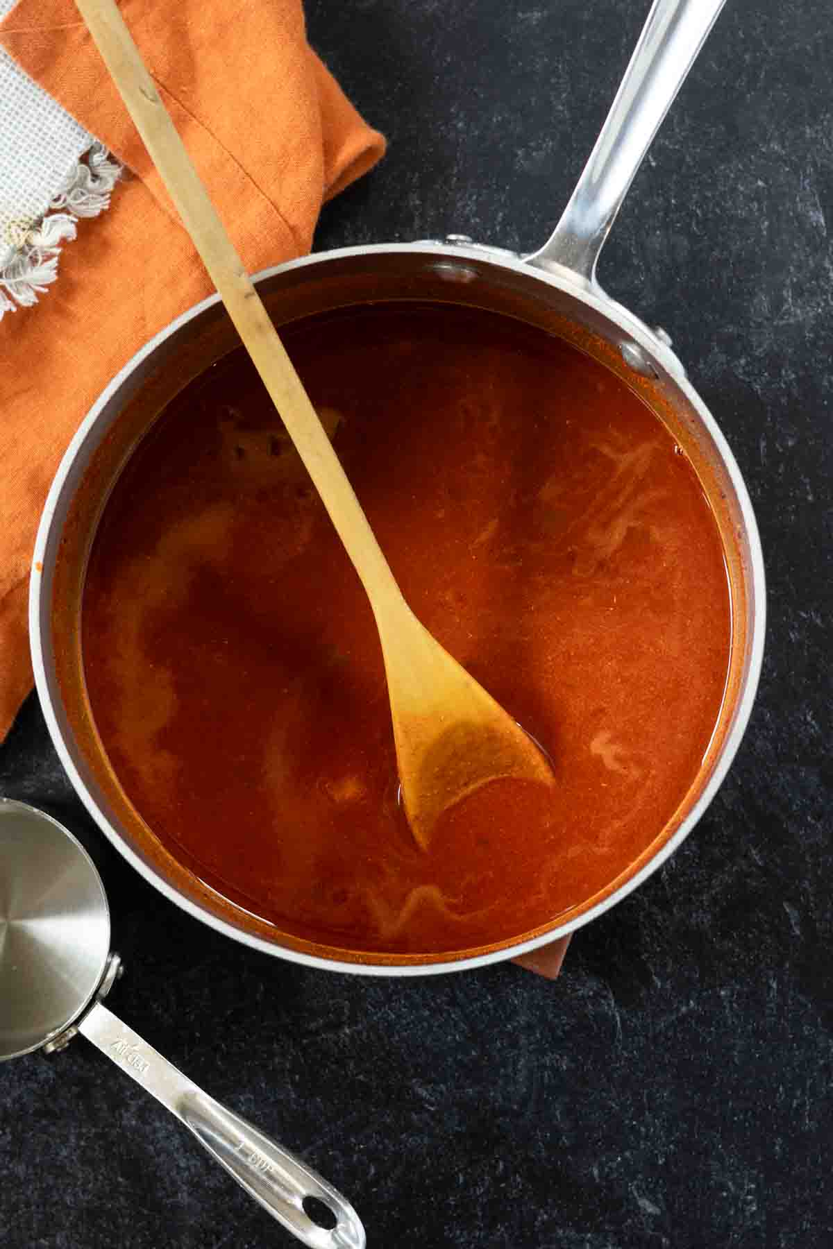 Cooking red chile sauce made from powder in a saucepan stovetop.