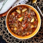 Hamburger potato soup served in an orange bowl.